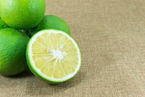 citrus fruit, samenstelling met bladeren Aan bruin kleding stof achtergrond foto