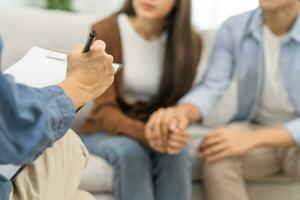 psychologie, depressie Aziatisch jong stel, geduldig overleg plegen probleem mentaal Gezondheid met psycholoog, psychiater Bij kliniek samen, man bemoedigend door Holding hand- van vrouw, behandeling Gezondheid zorg foto