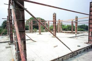 perspectief van betonnen kolommen in het stalen model staande op de cementvloer op de bouwplaats met heldere hemelachtergrond foto