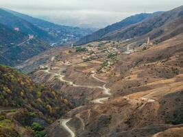 mooi keer bekeken van ingoesjetië. een weg aan de overkant de vallei. grote hoogte plateau met een berg serpentijn en herfst rotsachtig terrassen. hoog berg vallei. foto