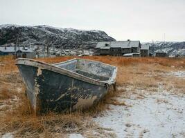 een roestig bevroren visvangst boot. oud visvangst dorp Aan de kust van de barentsz zee foto