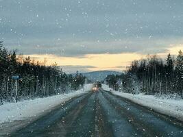 avond winter sneeuw weg Aan de kola schiereiland. verkeer van auto's. foto