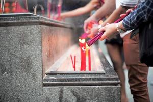 close-up handen met de bundel wierook voor verlichting met kaarsen in de zandbak foto