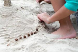 handen van meisje speelt met het zand op het strand versierd met dennenappels