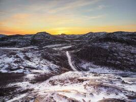 ijzig winter weg door de toendra heuvels in teriberka. verbazingwekkend kleurrijk arctisch landschap. foto