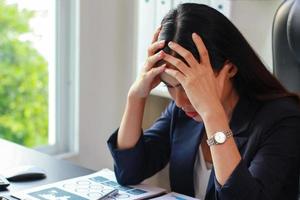 Aziatische zakenvrouw zittend op kantoor met stress, vrouwen zijn niet gelukkig op het werk. foto