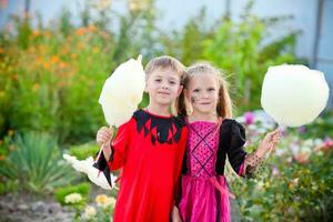 weinig jongen en meisje in kostuums van een heks en een beul voor halloween. kinderen Holding katoen snoep. kopiëren ruimte foto