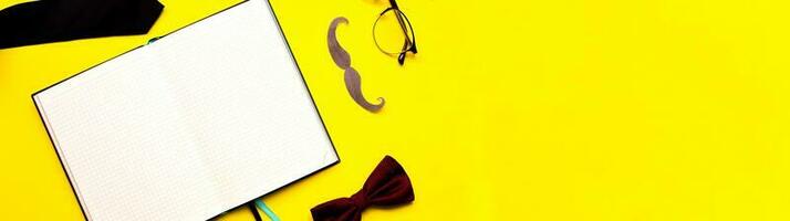 banier vlak leggen snor, bril, boog stropdas en stropdas Aan een geel achtergrond. mockup mannetje dagboek. mans bureau foto