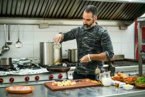 een chef is voorbereidingen treffen een maaltijd in de restaurants keuken. foto