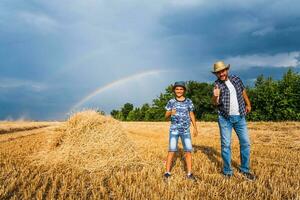 vader en zoon zijn staand in hun tarwe veld- na geslaagd oogst. foto