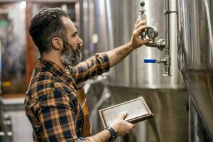 een brouwerij meester toezien op de bier productie werkwijze foto