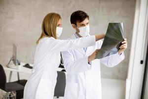 gemaskerde artsen die een röntgenfoto onderzoeken foto