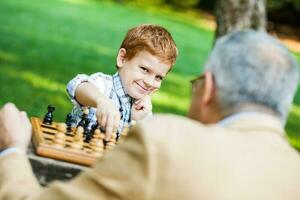 een opa en zijn kleinzoon spelen schaak foto