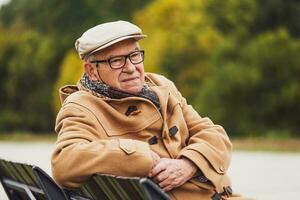 buitenshuis portret van een senior Mens resting Aan een bank foto