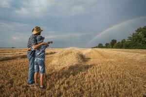 vader en zoon zijn staand in hun tarwe veld- na een geslaagd oogst. foto