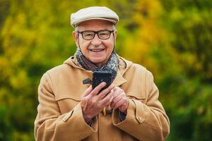 buitenshuis portret van een senior Mens controle zijn telefoon foto