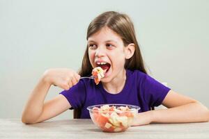 een meisje aan het eten een fruit salade foto