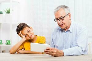 een opa uitgeven tijd met zijn kleinzoon Aan de tablet foto