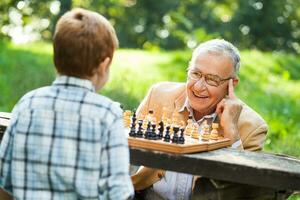 een opa en zijn kleinzoon spelen schaak foto