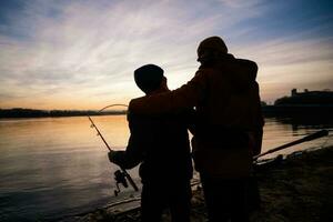 vader en zoon zijn visvangst Aan zonnig winter dag foto