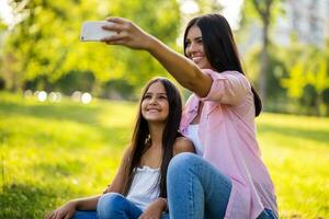 moeder en dochter nemen een selfie Bij de park foto