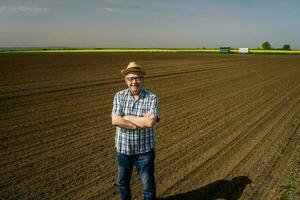 een senior boer staand in zijn eigen maïs veld- foto