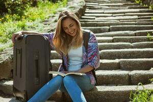 jong toerist vrouw zittend door de trap met een koffer foto