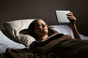 een vrouw lezing Aan een tablet foto