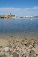 Malecon van la paz in baja california sur mexico met rotsen op het strand en nautische schepen onderaan blauwe lucht en zonnige ochtend met kalme zee foto