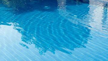 Doorzichtig water met teder golven. langs met mooi blauw zwemmen zwembad verdieping tegels. foto