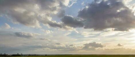 panorama van storm wolken over- de veld. mooi landschap Bij zonsondergang. bewolkt lucht banier foto