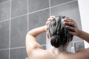 vrouw het wassen haar- met shampoo en douche in de badkamer. ai gegenereerd foto