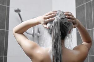 vrouw het wassen haar- met shampoo en douche in de badkamer. ai gegenereerd foto