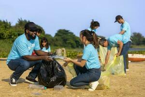 team van jong en verscheidenheid vrijwilliger arbeider groep genieten liefdadigheid sociaal werk buitenshuis in schoonmaak omhoog vuilnis en verspilling scheiding project Bij de rivier- strand foto