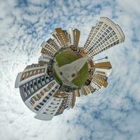 kleine planeet in blauwe lucht met wolken in het centrum in de buurt van moderne wolkenkrabbers of kantoorgebouwen. transformatie van bolvormig 360 panorama in abstracte luchtfoto. foto