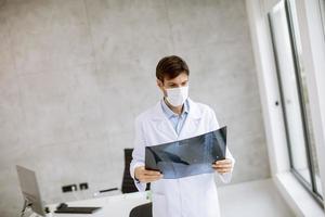 arts in een kantoor kijken naar een röntgenfoto foto