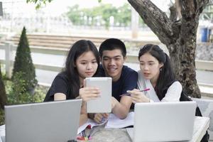 drie Aziatische studenten die een tablet gebruiken om te studeren