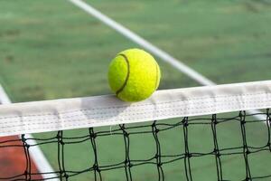 dichtbij omhoog van tennis bal clips de top van de netto. tennis bal raken de netto en gaat naar de andere kant. foto