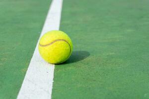 geel tennis bal Aan groen rechtbank en wit lijnen. top hoek visie van tennis bal Aan rechtbank. foto