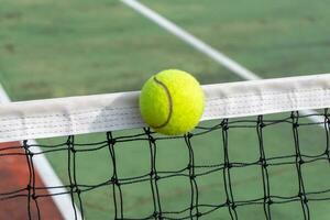 dichtbij omhoog van tennis bal clips de top van de netto. tennis bal raken de netto en gaat naar de andere kant. foto