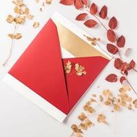 top visie van rood en gouden luxe uitnodiging kaart, envelop versierd met bladeren voor bruiloft of evenement concept. generatief ai. foto