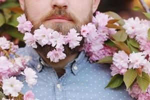 bebaarde man met kersenbloemen, portretclose-up op lenteachtergrond foto