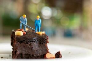 miniatuur mensen, een werknemer is maken een chocola brownie foto