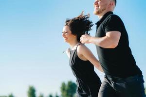 jong stel een man met een meisje in zwarte kleren lopen op het witte zand foto