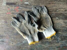 gebruikt bouw werk handschoenen, vuil handschoen Aan een hout achtergrond foto