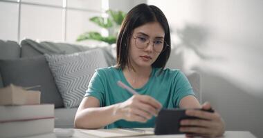 schattig meisje aan het leren online Aan smartphone in leven kamer foto