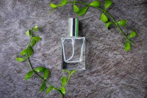 bovenaanzicht van een fles parfum omgeven met groene bladeren foto