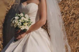 de bruid in een elegante trouwjurk heeft een mooi boeket foto