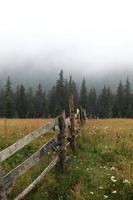 herfst weide met een oude houten hek op een close-up van de boerderij in de rokerige bergen foto