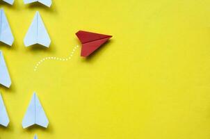top visie van rood papier vliegtuig origami weggaan andere wit vliegtuigen Aan geel achtergrond met aanpasbare ruimte voor tekst of ideeën. leiderschap vaardigheden concept en kopiëren ruimte foto